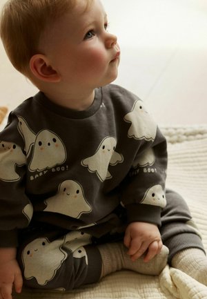 Szara bluza z białymi wzorami duchów i napisem "BABY BOO!". Miękka tkanina, okrągły dekolt, ściągacze przy rękawach, zestawiona z szarymi spodniami.