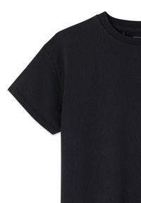 T-shirt noir à manches courtes en coton, avec un col rond et une texture lisse, présentant des coutures visibles le long des manches.