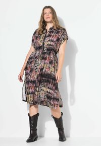 Šaty s krátkými rukávy a zapínáním na knoflíky v mnohobarevném abstraktním vzoru, s elastickým pasem a bočními rozparky, doplněné o černé kovbojské boty.