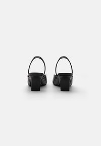 Svarte slingback-hæler med firkantet tå, chunky blokkhelt og glatt skinntekstur. Bakfra understreker designet det minimalistiske.