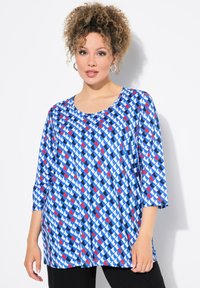 Tunic blu con un motivo geometrico in rosso, bianco e nero, con maniche 3/4 e scollatura tondeggiante, realizzata in un tessuto morbido.