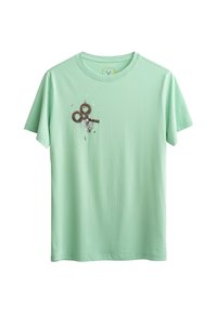 T-shirt verde menta a maniche corte in cotone morbido con una stampa grafica che presenta forbici vintage e dettagli astratti sul davanti.