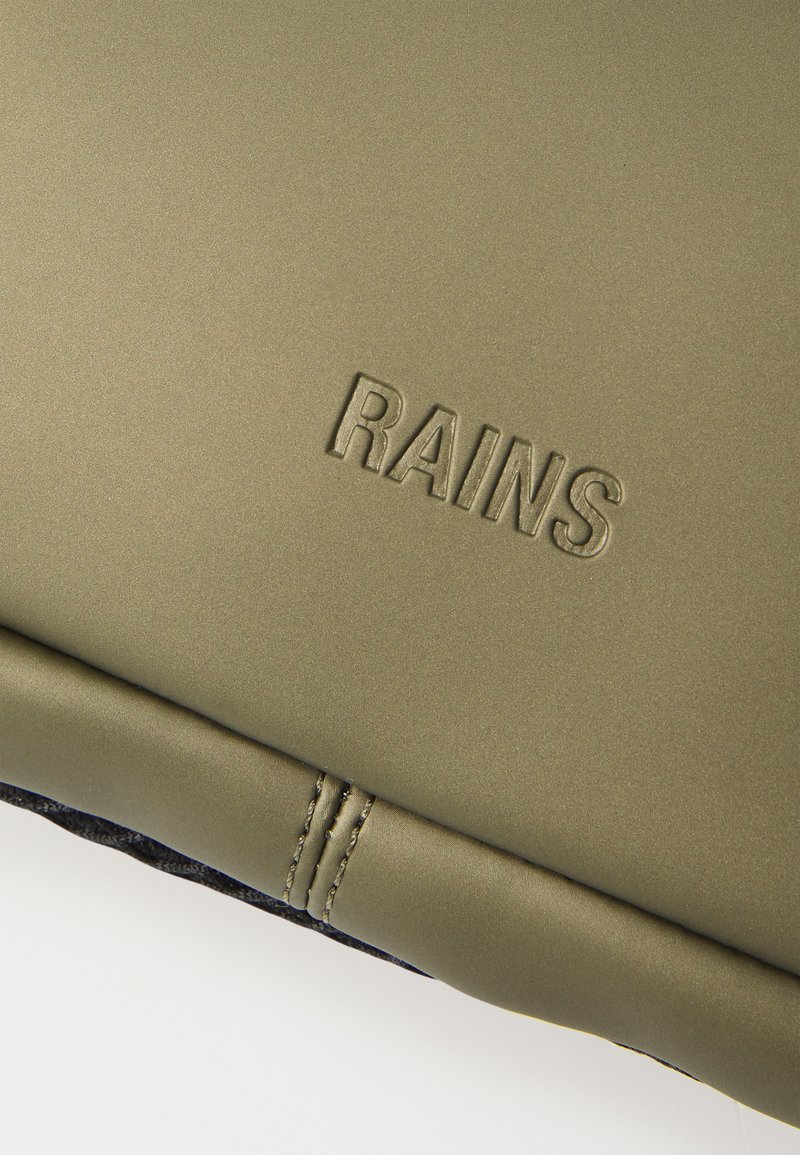 Prodotto Rains in verde oliva con una finitura opaca liscia, con branding in rilievo e cuciture a contrasto lungo i bordi.