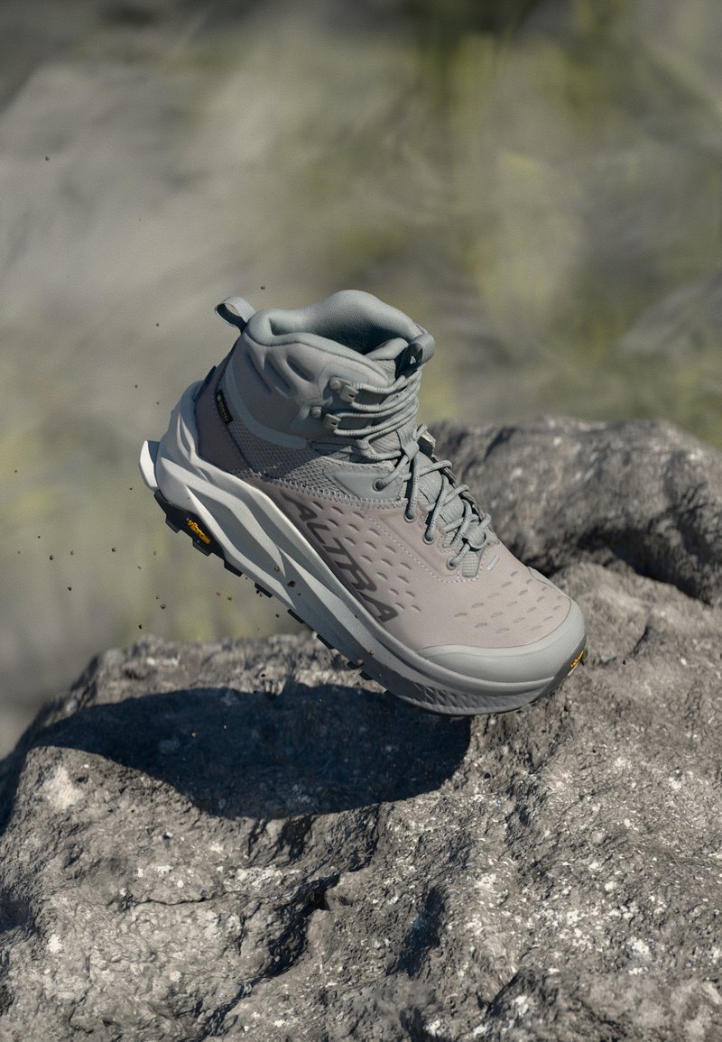 Harmaa vaelluskengät, joissa on teksturoitu päällinen, korkea nilkkatuki ja kestävä pohja. Varustettu näkyvällä logolla ja kevyellä rakenteella, sopii poluille.