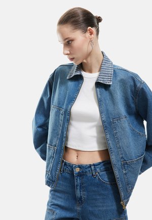 Denim jack met een gestreepte kraag, voorzien van twee voortassen, een rits sluiting en een iets oversized pasvorm. Draagt over een witte cropped shirt.