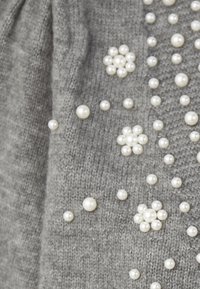 Szara dzianina ozdobiona skupiskami okrągłych białych pereł ułożonych w kwiatowe wzory oraz rozrzuconych indywidualnie.