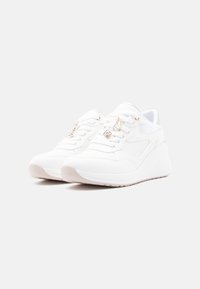 Baskets blanches avec tige texturée, col rembourré et semelle compensée. Dotées d'accents métalliques et de lacets plats pour la fermeture.