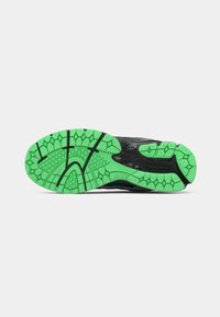 Semelle de chaussure de sport noire avec un design texturé. Comprend une semelle extérieure en caoutchouc vert avec des motifs hexagonaux pour une meilleure adhérence.