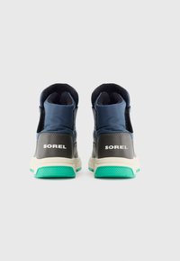 Sneaker in Blau mit grauen Akzenten, ausgestattet mit einer strukturierten Sohle, High-Top-Design und "SOREL"-Markierung in Weiß auf der Rückseite.