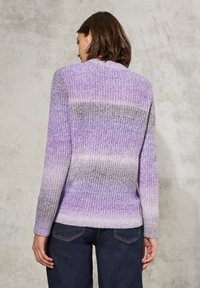 Pletený cardigan v odstínech fialové a šedé ombre. Má kulatý výstřih, dlouhé rukávy a žebrovaný lem. Nesený s tmavými džíny.
