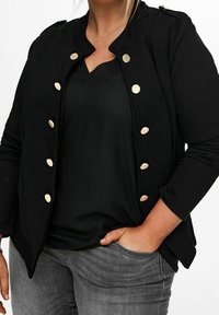 Czarna, casualowa kurtka z okrągłym kołnierzykiem, złotymi guzikami i długimi rękawami. Noszona na czarnej bluzce i zestawiona z szarymi dżinsami.