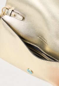 Clutch metálico dourado com textura suave, apresentando um detalhe decorativo azul, fecho de correr e múltiplos compartimentos para cartões no interior.