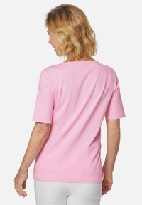 Kurze Ärmel, pinkes T-Shirt aus weichem Stoff, mit einem runden Halsausschnitt und glatter Textur, von hinten mit sichtbaren Nähten gezeigt.
