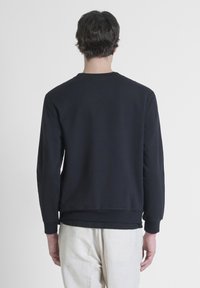 Sweat-shirt bleu marine avec des manches longues, des poignets et un ourlet côtelés. Tissu doux avec un col rond et sans logos ni motifs visibles.