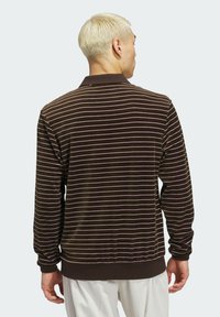 Brown long-sleeve polo featuring white and lavender horizontal stripes, ribbed cuffs, and a rib-knit collar, made from a soft textured fabric.
