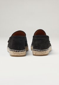 Espadrilles de ante negro con una suela de yute trenzado, diseño sin cordones y parte trasera reforzada con costuras a lo largo del borde.
