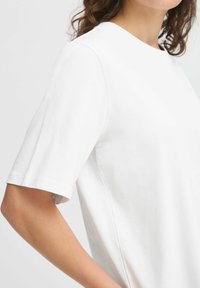 T-shirt bianco a maniche corte realizzato in morbido tessuto di cotone, con scollo rotondo e vestibilità rilassata con dettagli di cucitura in evidenza.