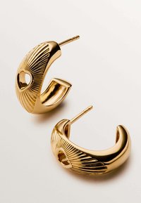 Pendientes de aro de oro con un diseño texturizado y acanalado, y una forma de corazón abierto en el centro. Acabado pulido con un cierre de pasador seguro.