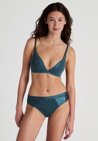 Teal lingerie set featuring a plunging, wire-free bralette with thin straps and a matching brief with a smooth waistband and minimal branding.