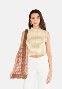 Žlutý a bílý vzorovaný crop top s volánkovým výstřihem a krátkými rukávy, spárovaný s pletenou taškou v růžové a hnědé barvě.