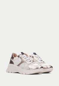 Sneaker metalliche argento e bianche con una finitura testurizzata, dotate di una suola spessa, lacci e dettagli in rete per la traspirabilità.