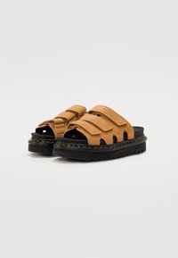 Sandali in suede marrone con due cinturini regolabili, punta aperta, suola in gomma nera e cuciture decorative lungo il bordo.