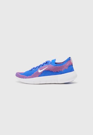 Blue mesh athletic shoe with pink accents, rounded toe, thin laces, and a white rubber sole. "Nike Free" branding on the heel.
