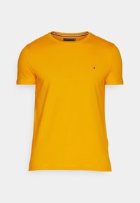 Senapsgul kortärmad t-shirt med rund halsringning och liten Tommy Hilfiger-logotyp på vänster bröst samt randig krage.