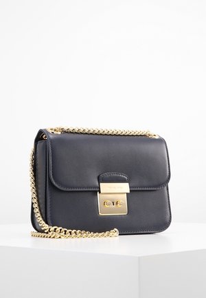 Czarna skórzana torebka na ramię z złotym łańcuszkowym paskiem i prostokątną złotą klamrą na przedniej klapie, prezentowana na białej powierzchni.