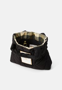 Schwarze gesteppte Handtasche mit gepolsterten Griffen, Innenfutter im beige Karo-Muster und einem vorderen Etikett mit der Aufschrift "South Shields."