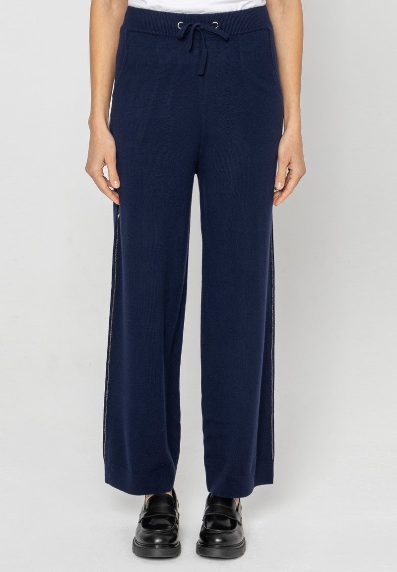 Granatowe spodnie wide-leg wykonane z miękkiego materiału dzianinowego, z elastycznym pasem i bocznymi suwakami dla dodatkowego akcentu. Gładka faktura w całej długości.