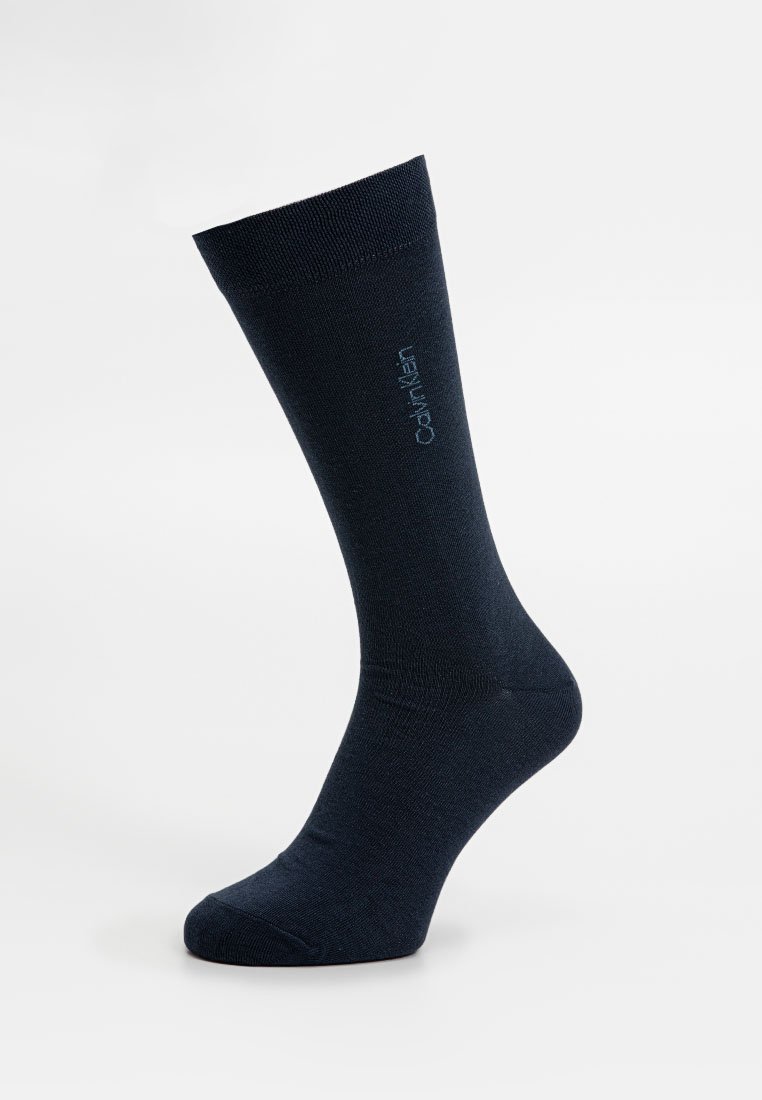 Dunkelblaue Socke aus glattem Stoff, mit einem gerippten oberen Teil und Logodetails an der Seite. Entwickelt für eine enge Passform und Komfort.