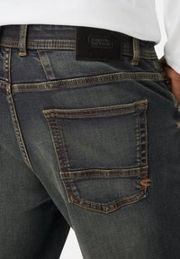 Granatowe dżinsy wykonane z denimu o teksturowym wykończeniu, z podwójnie przeszytą tylną kieszenią i czarną skórzaną metką w pasie.