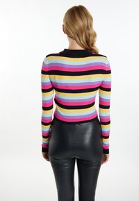 Suéter acanalado a rayas en tonos rosa, negro, amarillo y azul, con mangas largas y un diseño ajustado, combinado con pantalones de cuero negros y ajustados.