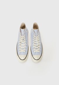 Světle modré vysoké tenisky z plátna s bílými tkaničkami, gumovým špičkovým krytem a černým lemem. Logo na vnější straně.