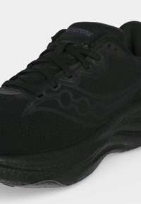 Черна маратонка Saucony с връзки и текстурирана подметка, представяща странично лого и дишащ горен материал.
