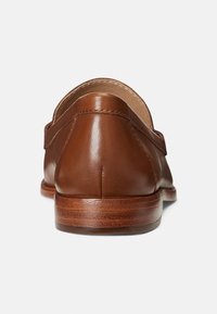 Hnědé kožené mokasíny s kulatou zadní částí, hladkým povrchem a dřevěnou podrážkou. Viditelné švy a čistý, minimalistický design.