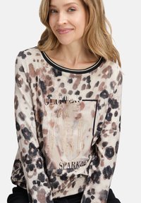 Langsleeve top met luipaardprint in beige en zwart, met glitteraccenten, voorzien van een ronde hals en een zachte textuur.