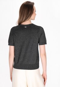 Kortærmet sort glitrende sweater med rund halsudskæring og ribbet kant, der har subtile metaltråde for tekstur og glans.