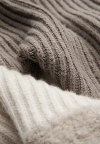 Deux morceaux de tissu en tricot texturé, l'un beige clair et l'autre marron gris foncé, tous deux dotés de fines nervures et d'une douceur agréable.