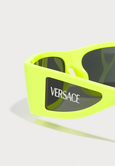 Neoonkollased prillid kolmnurksete raamidega, tumepruunid läätsed ja hõbedane "VERSACE" logo küljes. Siledast plastikust materjal.