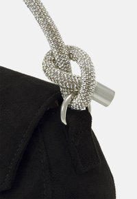 Czarna zamszowa torebka z dodatkiem srebrnych kryształków ozdabiających węzeł na pasku oraz metalicznym akcentem przy otwarciu.