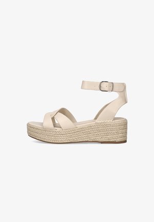 Sandalias de plataforma beige con correas entrecruzadas, hebilla en el tobillo y una suela intermedia estilo esparto tejida. Parte superior de cuero suave con suela plana.