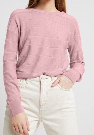 Pink striped knit sweater with wide neckline and ribbed cuffs, worn over high-waisted white jeans with a button and pocket detail.