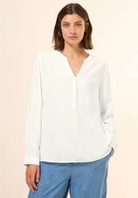 Witte blouse met lange mouwen en V-hals, voorzien van een knoopsluiting, gemaakt van een zachte stof, met manchetdetails en een ontspannen pasvorm.