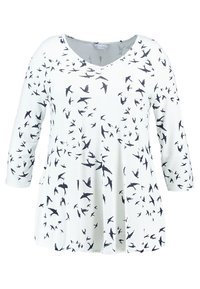 Tunic bianca con scollatura a V, maniche a 3/4 e stampa di uccelli neri sparsi. Realizzata in tessuto morbido con un fit rilassato.