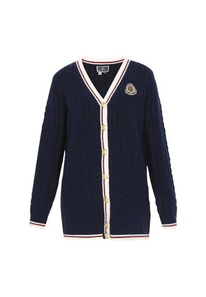 Dunkelblauer Kabelstrick-Cardigan mit V-Ausschnitt, cremefarbenem und weinrotem Streifenbesatz, sechs goldenen Knöpfen und einem Badge-Detail auf der linken Brust.