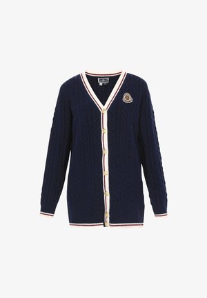 Tummansininen kaulakutoilla neulottu neuletakki, jossa on V-pääntie, kerma- ja marjapuuron raidoitus, kuusi kultaa nappia ja merkkiyksityiskohta vasemmassa rinnassa.