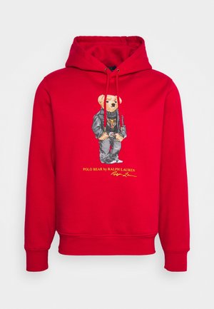 Felpa con cappuccio rossa con un orsetto che indossa una giacca di pelle nera e jeans, con il testo "Polo Bear by Ralph Lauren" in basso.