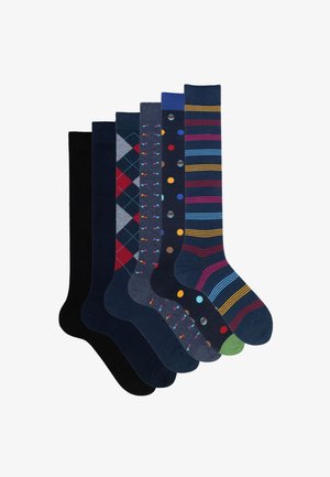 Collezione di sei paia di calzini: nero uniforme, blu navy con motivo argyle, grigio con pois colorati, a righe in vari colori e altri due design decorati.